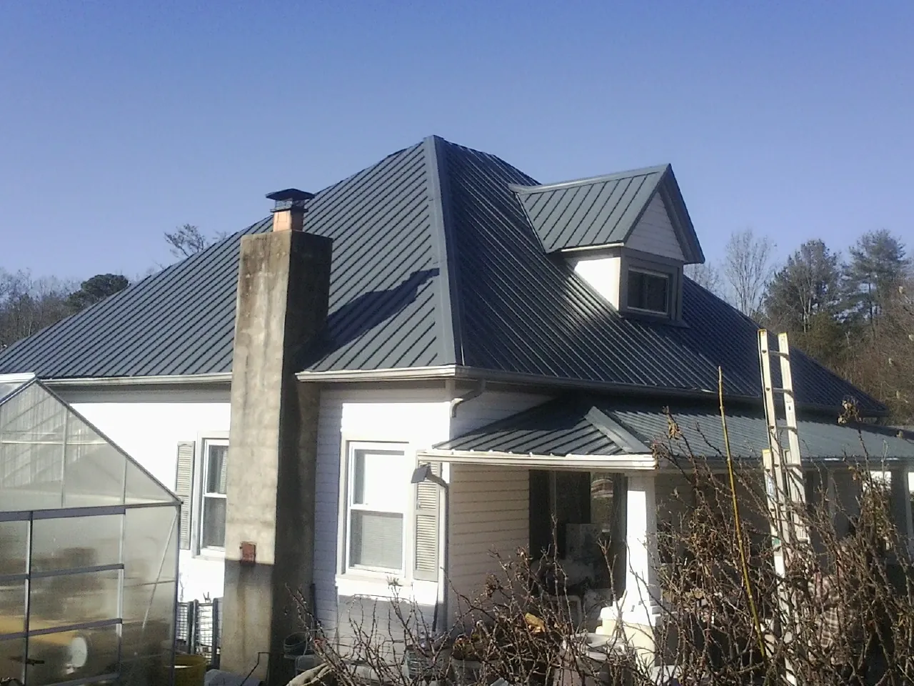 Dark blue standing seam metal roof on a white farmhouse with dormer — Slate & Tile Roof Repair by Roofing Brothers in Costa Mesa