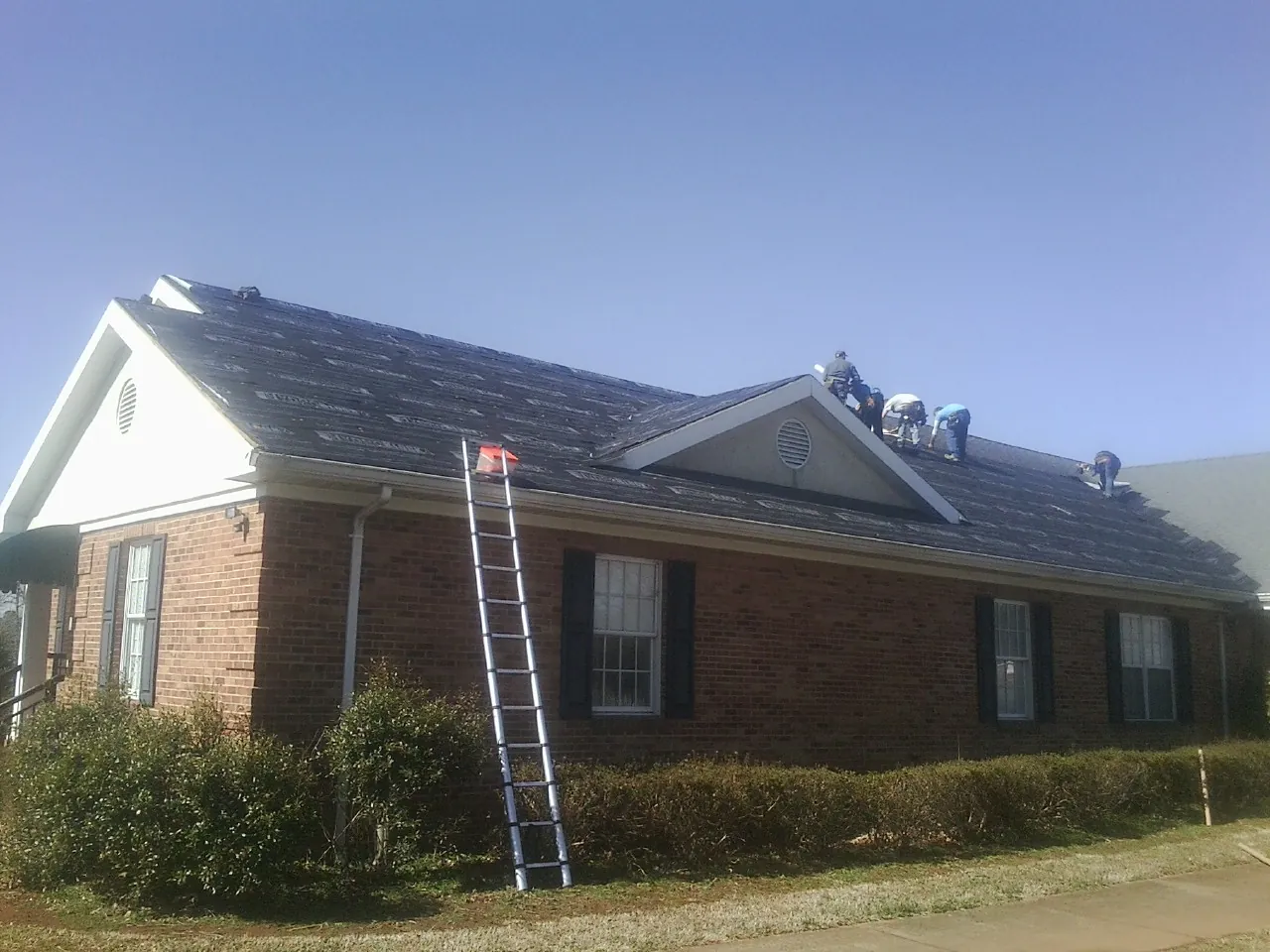 Crew tearing shingles off a brick ranch roof with a ladder set — Metal Roof Repair work by our crew in Costa Mesa