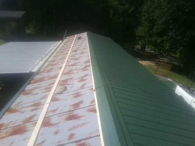 Old rusted panels beside newly installed green metal roofing — Wind Damage Roof Repair by Roofing Brothers in Costa Mesa