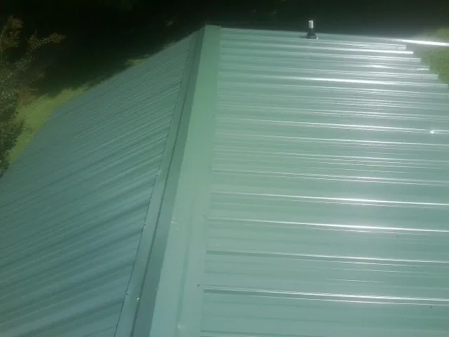 New green metal panels meeting at the ridge of a roof — Flat Roof Repair work by our crew in Costa Mesa