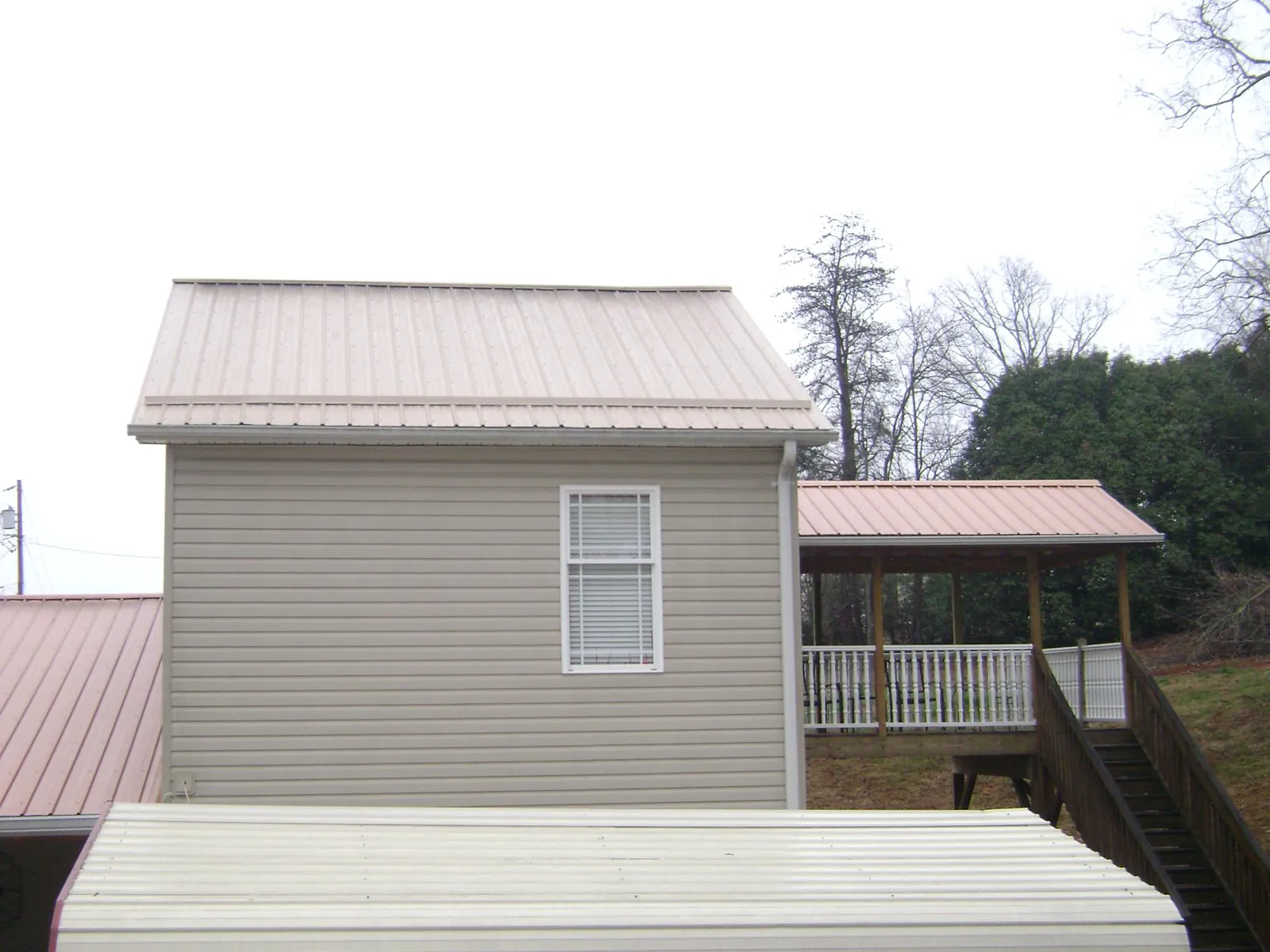 Tan metal roofs on a two story addition and attached porch, from a Roof Replacement job in Costa Mesa